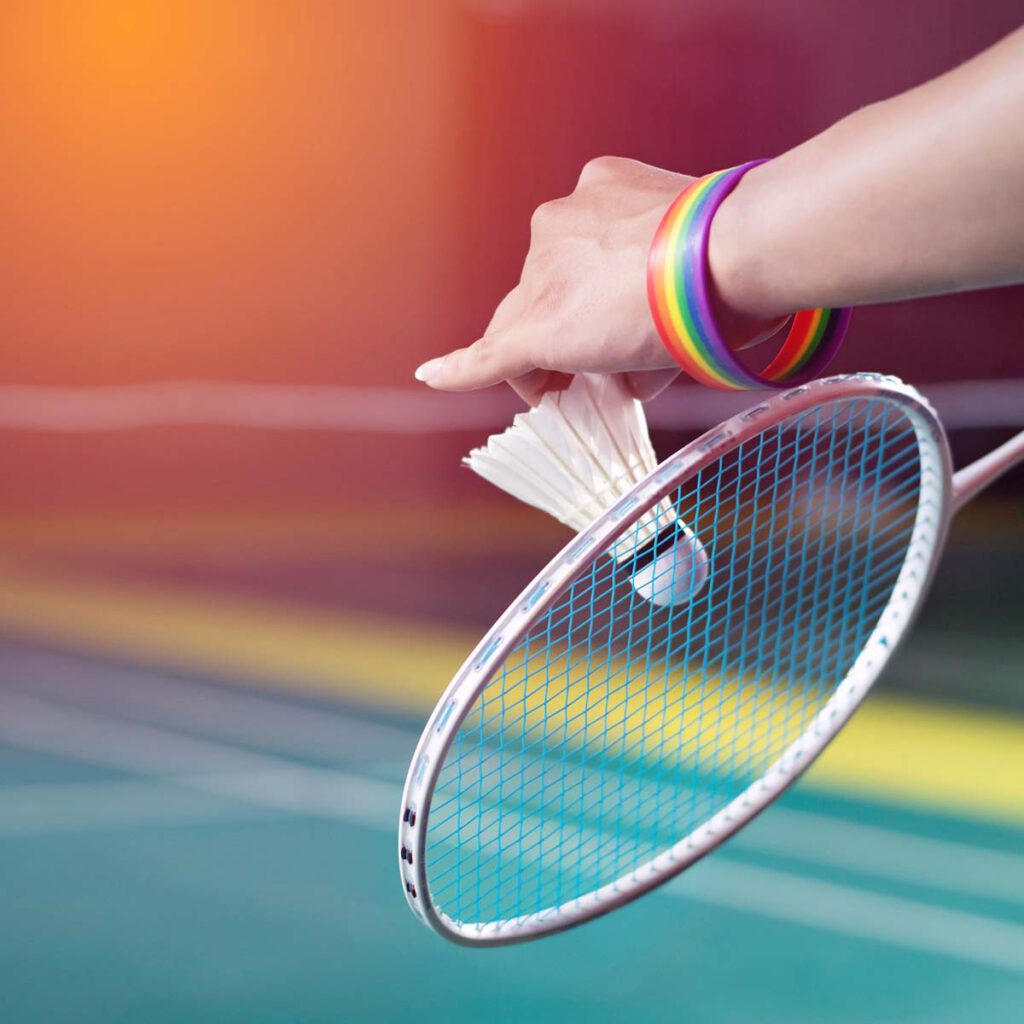 Eine Person hält einen Badmintonschläger und trägt ein Regenbogenarmband.