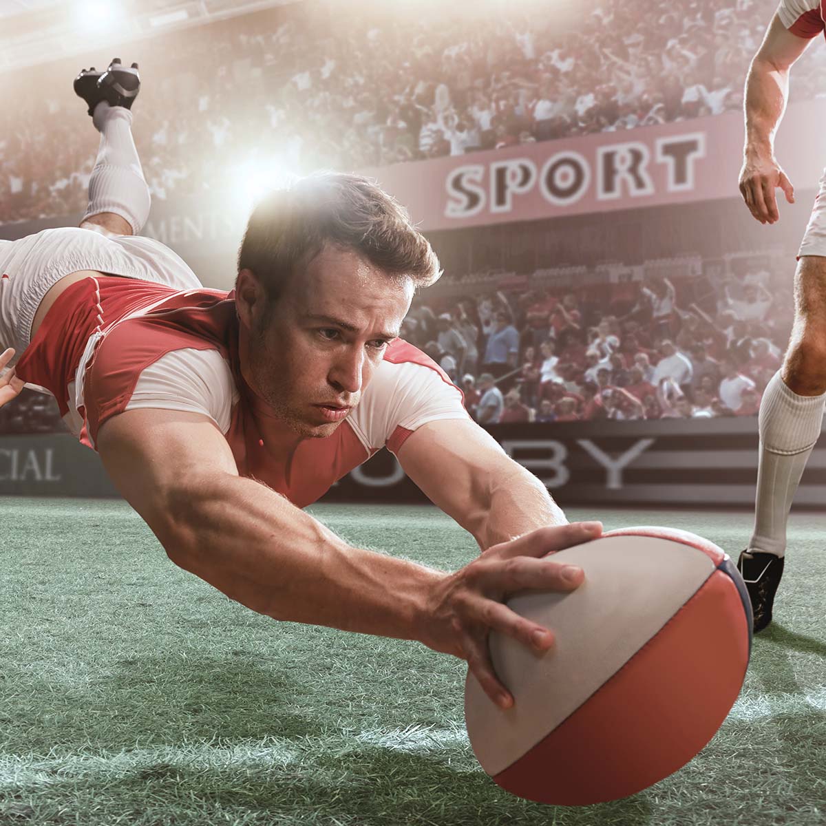 Rugbyspieler springt nach dem Ball und streckt sich auf dem Rasen aus.